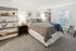 Inviting bedroom with plush bed, stylish shelves, and warm natural light through a large window, perfect for relaxation.
