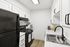 Sleek modern kitchen with elegant white cabinetry, high-end black appliances, and a spacious countertop perfect for culinary creations.