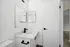 Bright and modern bathroom featuring sleek black fixtures, a stylish vanity with a large mirror, and a contemporary design.