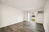 Spacious and bright living room with elegant wood flooring, pristine white walls, and large sliding glass doors leading to an inviting patio area.