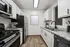 Modern kitchen with sleek stainless steel appliances, elegant white cabinetry, and granite countertops on a warm wooden floor.