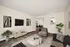 Chic and modern living room with elegant decor, a flat-screen TV, stylish furniture, and a glimpse into a cozy dining area.