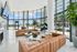 Luxurious apartment lobby with modern design, featuring elegant leather seating, marble floors, and a panoramic view through floor-to-ceiling windows.