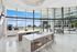 Luxurious and bright community lounge showcasing a sleek kitchen island, modern bar stools, and stunning floor-to-ceiling windows with views of the vibrant urban landscape.