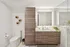 Elegant modern bathroom featuring sleek wood cabinetry, large illuminated mirror, and luxurious shower area.