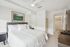 Bright and inviting bedroom with a plush bed, modern ceiling fan, and stylish decor leading to a spacious walk-in closet.