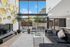 Luxurious living room with high ceilings, elegant decor, and expansive windows offering natural light and a view of the patio.