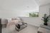 Bright and cozy living space with stylish furnishings, large window offering lush views, and a chic plant accent adding a touch of nature.