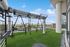 Spacious rooftop gym with modern fitness equipment, surrounded by lush greenery and offering stunning cityscape views.