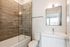 Modern bathroom featuring elegant wood-like tiles, a sleek glass-enclosed shower, and contemporary fixtures.
