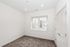 Bright, unfurnished bedroom with large window and plush carpet, offering natural light and a modern ambiance.