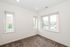Bright and inviting room with large windows offering a pleasant view, cozy carpeted floor, and freshly painted walls.