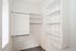 Bright and spacious walk-in closet with modern shelving and hanging space, perfect for organized storage.