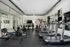 Modern fitness center with state-of-the-art equipment including treadmills, rowing machines, and weights, featuring floor-to-ceiling windows for a bright workout space.