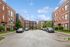 Modern apartment complex with stylish brick facades and lush greenery on a sunny day, featuring ample parking and elegant architecture.