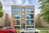 Modern multi-story brick apartment building with large windows and a landscaped front yard, offering urban living with style and natural light.