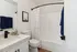 Modern bathroom with elegant white countertop, sleek black fixtures, and a geometric shower curtain, creating a fresh and stylish ambiance.