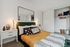 Chic bedroom with modern lighting, a plush green headboard, stylish throw pillows, and an inviting open closet.