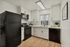 Modern kitchen with sleek black appliances, white cabinetry, and elegant wood flooring, filled with natural light.