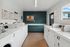 Modern laundry room featuring top-of-the-line washing machines and dryers, accented by a stylish blue wall and natural light from large windows.
