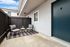 Charming outdoor seating area featuring modern black chairs and a stylish patterned rug against a sleek gray exterior.