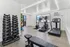 Modern fitness room with state-of-the-art treadmill, exercise bike, and dumbbell rack, set in a bright space with sleek design.