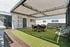 Chic outdoor lounge area with modern furniture, vibrant green artificial turf, and a stylish pergola with string lights.