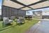 Chic outdoor living space with modern lounge furniture, canopy shade, and a stylish BBQ grill on lush artificial grass.
