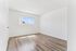 Bright, airy bedroom with sleek wood flooring and a large window offering a clear sky view, perfect for natural light lovers.