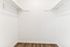 Spacious walk-in closet with elegant wooden flooring and ample shelving, perfect for organized living.