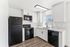 Modern kitchen with sleek black appliances, bright white cabinetry, and elegant wood flooring, ideal for culinary creativity.