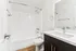 Elegant and modern bathroom featuring a sleek white bathtub and stylish dark wood vanity with a polished countertop.