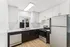 Modern kitchen with sleek stainless steel appliances, elegant white cabinetry, and natural light from a wide window, featuring a stylish open design.