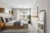 Bright and inviting bedroom featuring a stylish wooden bed with plush gray pillows, modern side tables, and elegant decor. Natural light pours through the large window, enhancing the room's cozy ambiance.