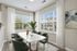 Elegant dining area with a modern white table and chic green chairs, featuring large windows with scenic views and ample natural light.