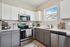 Modern kitchen with sleek stainless steel appliances, bright cabinetry, and a sunlit window creating a welcoming culinary space.