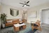 Chic living room with a stylish brown leather sofa, decorative green tapestry, and modern ceiling fan. Features a cozy wood armchair, sleek marble-top coffee table, and lush indoor plant.