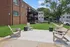 Inviting outdoor seating area at modern apartment complex, featuring lush green lawns and stylish wooden chairs under clear blue skies.