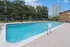 Inviting outdoor pool area with modern seating, surrounded by lush greenery and a city skyline backdrop.