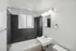 Modern bathroom with sleek black tiles, a pristine white bathtub, and elegant lighting, ideal for relaxation and style.