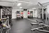 Modern home gym with a variety of weights, sleek workout equipment, and stylish black-and-white floral wallpaper.