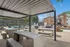 Inviting outdoor area featuring modern seating under a stylish pergola with string lights, adjacent to a pool and playground.