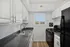 Bright modern kitchen with sleek black countertops, stainless steel sink, and white cabinetry under natural light.