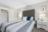 Elegant bedroom featuring a plush gray tufted headboard, soft patterned bedding, and modern nightstands with stylish lamps.