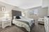 Elegant bedroom with plush grey headboard, cozy bedside lamps, and a window view, creating a welcoming and serene atmosphere.