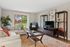Inviting living room with elegant decor, featuring a large window with scenic view, cozy seating, vibrant rug, and stylish entertainment center.