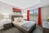 Inviting bedroom with modern decor, vibrant red curtains, and a scenic view through large windows.