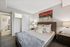 Cozy bedroom featuring a plush bed with elegant bedding, modern artwork, and ambient lighting next to an en-suite bathroom.