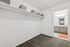 Spacious walk-in closet with shelving and view into a modern bathroom, featuring sleek cabinetry and bright lighting.