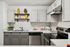 Modern kitchen with sleek gray cabinetry, white subway tile backsplash, and stainless steel appliances. Bright shelving featuring vibrant yellow decor adds a stylish touch.